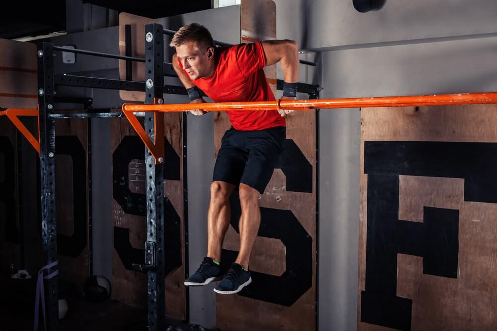 mężczyzna wykonuje muscle up na drążku