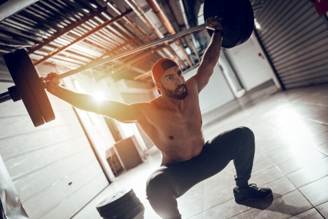 mężczyzna wykonuje overhead squat - przysiad ze sztangą