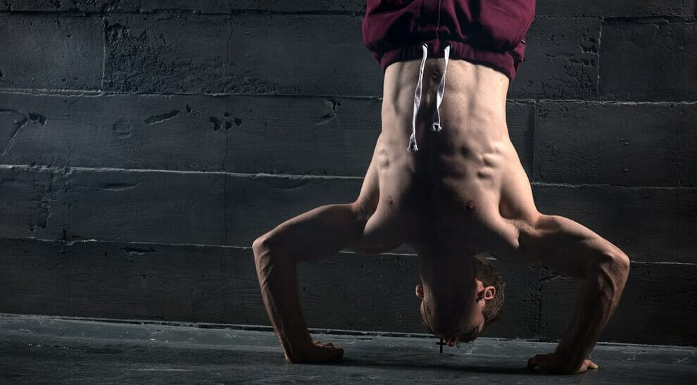 mężczyzna robi push up hand stand na klatkę i barki